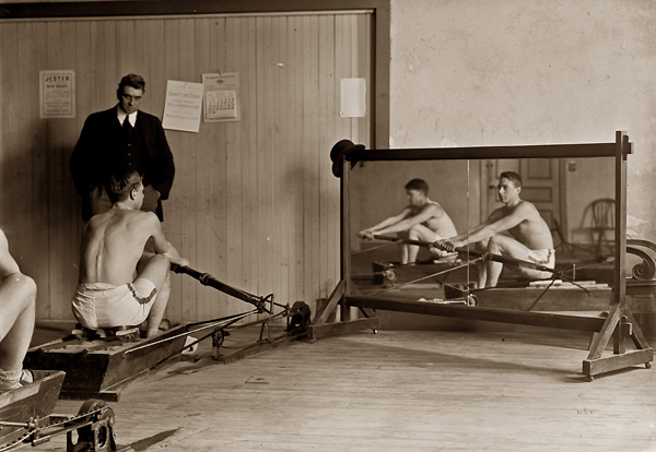 Man on rowing machine with reflection in mirror - Click Image to Close