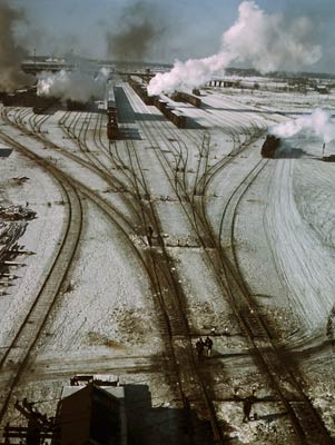 Steam rising from trains in snow covered tracks